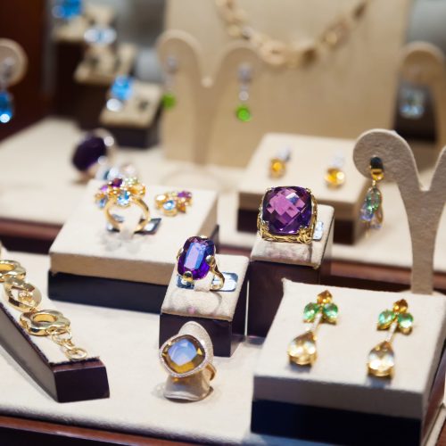 Gold jewelry with gems at showcase of jewelry shop